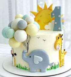 a birthday cake with an elephant, giraffe and balloon topper on it