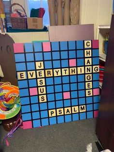 a large scrabble board sitting on the floor next to other pieces of art