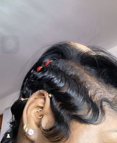 the back of a woman's head with ear piercings and hair in it