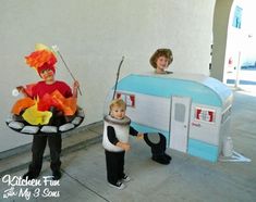 two children in costumes standing next to an old camper trailer and one boy holding a fishing rod