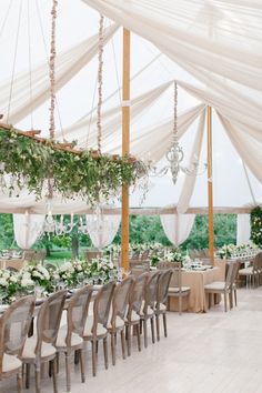 an indoor wedding venue with white drapes and greenery