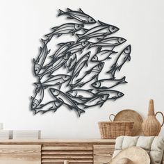 a metal fish sculpture on the wall next to a chair and basket in front of it