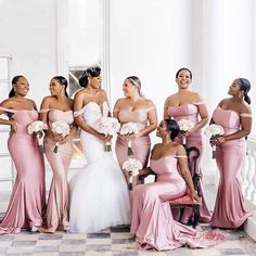 a group of women standing next to each other in pink dresses and holding bouquets