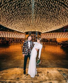 a bride and groom pose for a photo in front of the lights