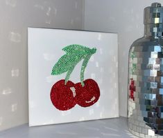 a painting on a shelf next to a vase and mirror ball mosaic wall hangings