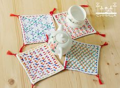 four placemats on a wooden table with one tea pot and the other two