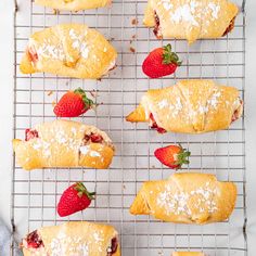 strawberry croissants on a cooling rack with powdered sugar and strawberries