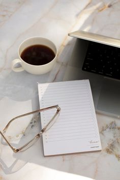 a laptop computer sitting on top of a table next to a cup of coffee and eyeglasses