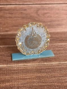 a glass plate sitting on top of a wooden table next to a blue plaque with an arabic calligraphy