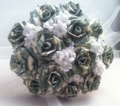 a bouquet made out of dollar bills and flowers on a white table cloth with veil