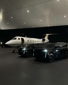 two cars parked in front of a private jet and an airplane on the tarmac