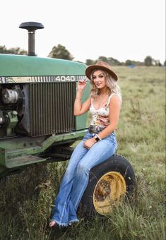 a woman sitting on top of a tractor in a field