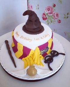 a birthday cake with a wizard hat and some scissors on it's side, sitting on top of a table