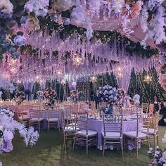 an outdoor wedding setup with purple flowers and chandeliers