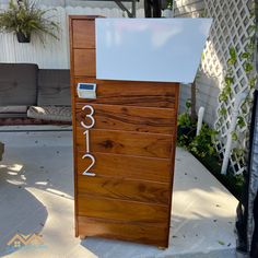 a wooden door with numbers on it in front of a white fence and some plants