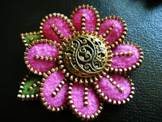 a pink flower brooch sitting on top of a black surface