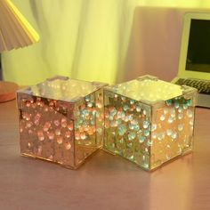 two clear cubes sitting on top of a wooden table next to a laptop computer