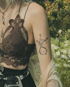 a woman with a tattoo on her arm is sitting in front of flowers and plants