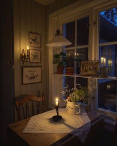 a table with a tea pot on it in front of a window filled with candles