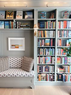 a living room filled with lots of books on top of a book shelf next to a couch