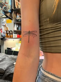 a woman's arm with a small dragonfly tattoo on the left side of her arm