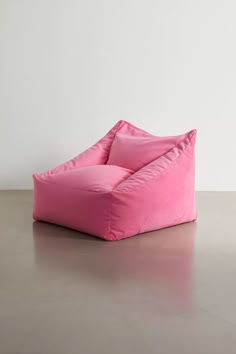 a pink bean bag chair sitting on top of a cement floor next to a white wall