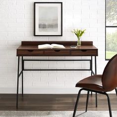 a desk with a book and some flowers on it in front of a white brick wall