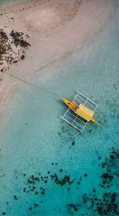 an aerial view of a yellow boat in the water next to a sandy beach and shore