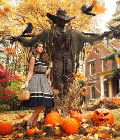 a woman standing next to a scarecrow and pumpkins