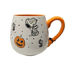 a white and orange coffee mug with halloween images on it