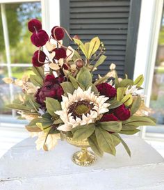 a vase filled with red and white flowers on top of a table next to a window