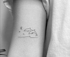 a small dolphin tattoo on the left inner arm, with stars and moon in the background