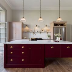 a large kitchen with an island in the middle and two lights hanging from the ceiling