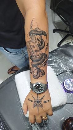 a man with a tattoo on his arm and wrist is holding a watch in one hand