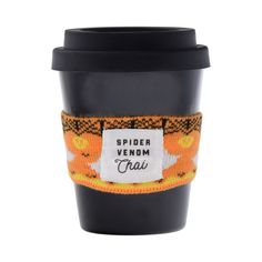 a black cup with an orange and yellow label on it, sitting next to a white background