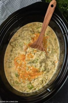 a wooden spoon in a black crock pot filled with broccoli and cheese