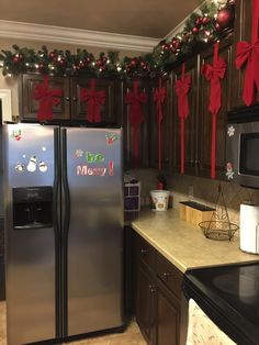 a kitchen decorated for christmas with lights and decorations on the wall, refrigerator freezer