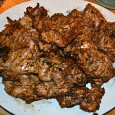 a white plate topped with meat on top of a wooden table