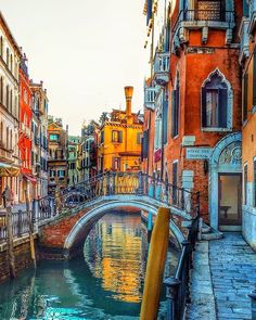 an old bridge over a small canal in the middle of a city with buildings on both sides