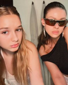 two young women wearing sunglasses are sitting next to each other