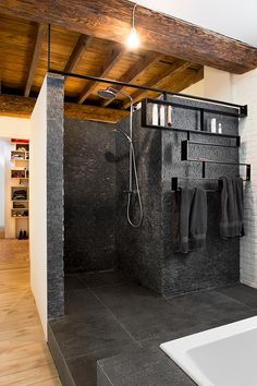 a bathroom with black tile and wooden ceiling