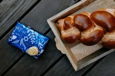 some bread on a wooden tray next to a blue bag