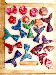 there are many different colored sea creatures on the cutting board with a wooden spatula