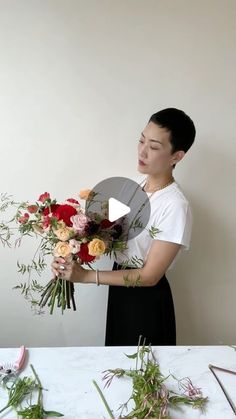 a woman holding flowers in front of a white wall