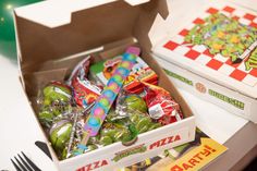 a box filled with candy sitting on top of a table next to a fork and knife