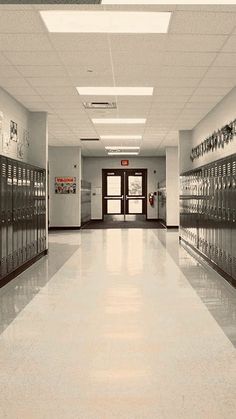 an empty hallway with many lockers and doors