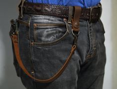 a man wearing jeans and a belt is standing with his back to the camera