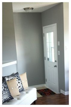 a living room with a white door and some pillows