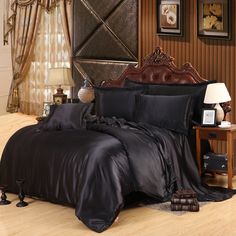 a bed with black sheets and pillows in a room