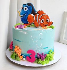 a blue cake with two clown fish on top and an under the sea theme decoration